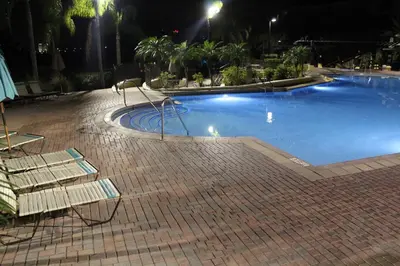 a swimming pool at night with two lounge chairs next to it at Viz Cay Apartment 202 in Orlando