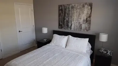 a bedroom with a bed with white sheets and two lamps at 4 Bedroom Private Lakefront Town Home at Storey Lake near Disney World Parks in Kissimmee