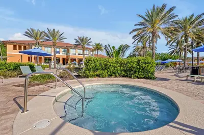 a hot tub in the middle of a patio with palm trees at Regal Oaks Resort Vacation Townhomes by IDILIQ in Orlando