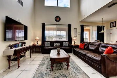 a living room with a leather couch and a piano at Margaritavilla at Emerald Island in Kissimmee