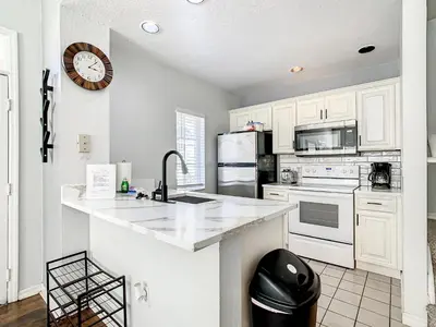 a kitchen with white appliances and a clock on the wall at 4 Bedroom Townhouse in a Gated Resort! in Kissimmee