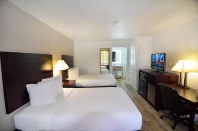a hotel room with two beds and a desk and a television at Hotel Monreale Express & Studios IDrive District in Orlando