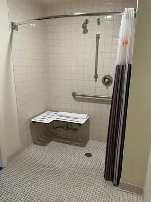 a bathroom with a shower with a bench in it at Baymont by Wyndham Orlando South in Orlando