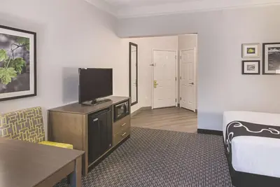 a living room with a tv and a room with a bed at La Quinta by Wyndham Orlando UCF in Orlando