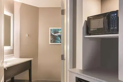 a small room with a microwave and a room with a kitchen at La Quinta by Wyndham Orlando UCF in Orlando