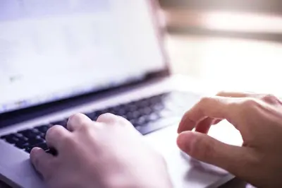 a person is typing on a laptop computer at La Quinta by Wyndham Orlando UCF in Orlando