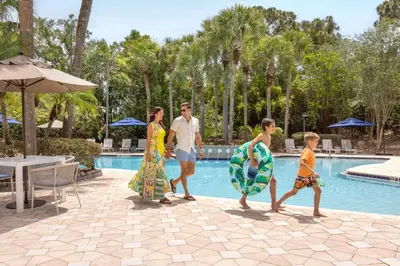 a family walking by the pool at a resort at DoubleTree Suites by Hilton Orlando at Disney Springs in Orlando