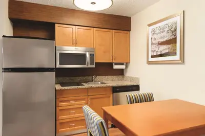a kitchen with a table and a stainless steel refrigerator at Homewood Suites by Hilton Orlando-International Drive Convention Center in Orlando