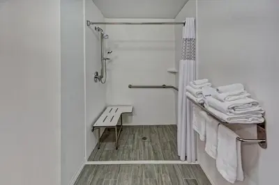 a bathroom with a shower and a bench and towels at Hampton Inn & Suites Clermont in Clermont