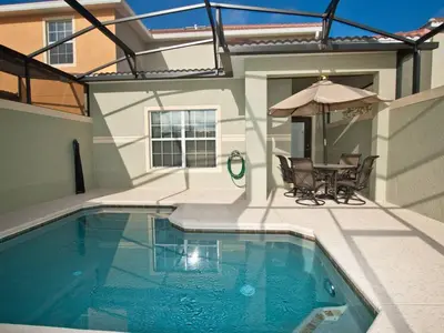a swimming pool with a table and an umbrella at Beautiful Waterfront Townhome Wsplashpool-3024 in Kissimmee