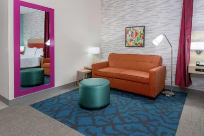 a living room with a chair and a mirror at Home2 Suites By Hilton Orlando Near Universal in Orlando