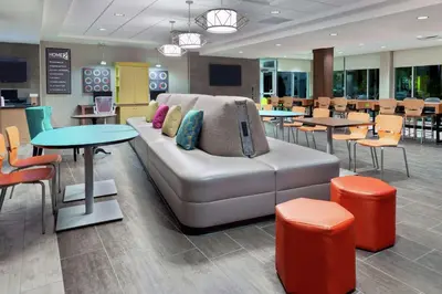 a living room with a couch and tables and chairs at Home2 Suites By Hilton Orlando Near Universal in Orlando