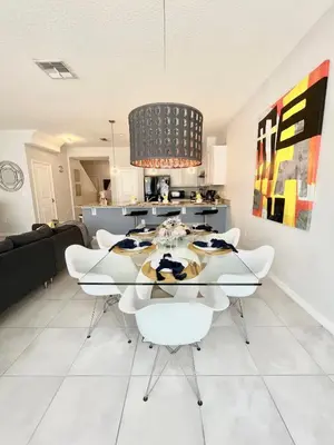 a dining room with a glass table and white chairs at Home Away From Home in Kissimmee