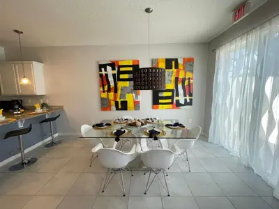 a dining room with a glass table and white chairs at Home Away From Home in Kissimmee