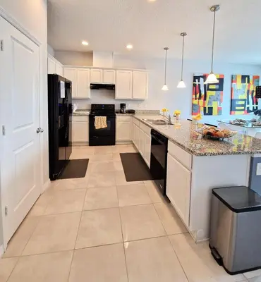 a kitchen with white cabinets and a black refrigerator at Home Away From Home in Kissimmee