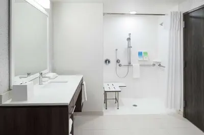 a white bathroom with a shower and a sink at Home2 Suites By Hilton Orlando Airport in Orlando