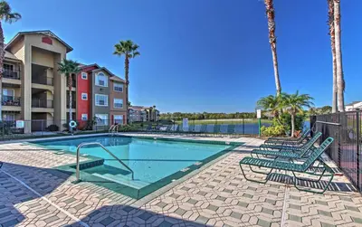 a swimming pool with lounge chairs and palm trees at Disney Adjacent in Kissimmee