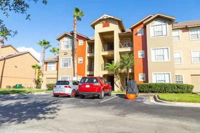 two cars parked in a parking lot in front of a building at Disney Adjacent in Kissimmee