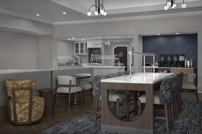a kitchen with a bar with chairs and a counter at Homewood Suites by Hilton Orlando Airport in Orlando