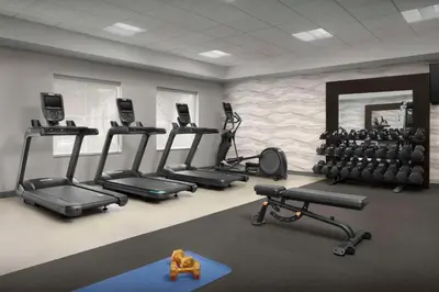 a gym with several tread machines and a mirror at Homewood Suites by Hilton Orlando Airport in Orlando
