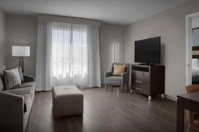 a living room with a tv and a couch and chair at Homewood Suites by Hilton Orlando Airport in Orlando