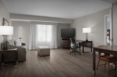 a living room with a bed and a desk and a television at Homewood Suites by Hilton Orlando Airport in Orlando