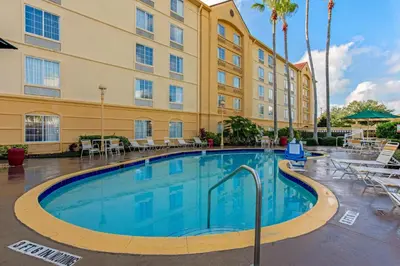 a pool in front of a hotel with a building at La Quinta by Wyndham Orlando Airport - On Property Food Trucks & Free Airport Shuttle! in Orlando