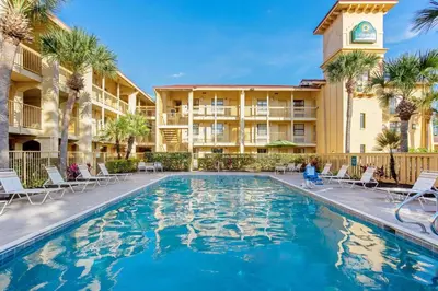 a swimming pool in front of a hotel with palm trees at La Quinta Inn by Wyndham Orlando Airport West in Orlando