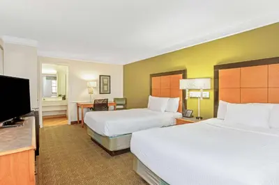 a hotel room with two beds and a flat screen tv at La Quinta Inn by Wyndham Orlando Airport West in Orlando