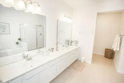 a white bathroom with two sinks and a large mirror at Modern Vacation Apartment with a Lake View in Orlando