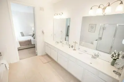 a white bathroom with a large tub and a sink at Modern Vacation Apartment with a Lake View in Orlando