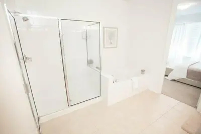 a white bathroom with a shower with a glass door at Modern Vacation Apartment with a Lake View in Orlando