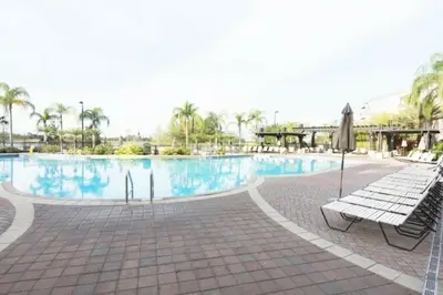 a swimming pool with two benches and an umbrella at Modern Vacation Apartment with a Lake View in Orlando