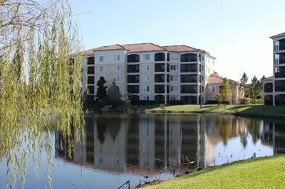 a large apartment building next to a body of water at WQR Private Rentals No Resort Pool Access in Orlando