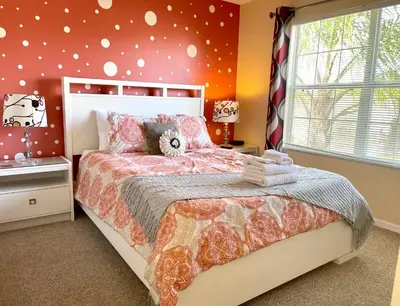a bedroom with a large bed with orange walls at Disney Dream with Hot Tub, Pool, Xbox, Games Room, Lakeview, 10 min to Disney, Clubhouse in Kissimmee