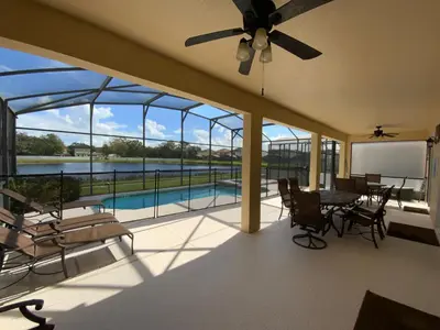 a screened in porch with a table and chairs and a pool at Seasons Villa 6 bedrooms, 4 masters and water view in Kissimmee