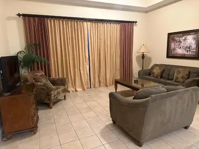 a living room with a couch and a tv and chairs at Penthouse Close to Disney area and Malls water view in Orlando