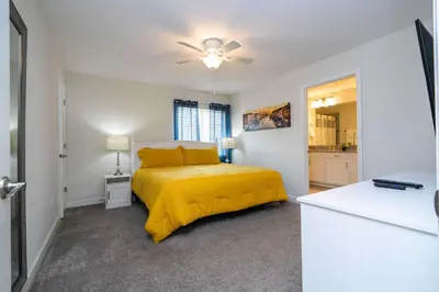 a bedroom with a yellow bed and a kitchen at Stunning 5 Bd Home w/ Pool Close to Disney 4822 in Kissimmee