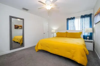 a bedroom with a yellow bed and a mirror at Stunning 5 Bd Home w/ Pool Close to Disney 4822 in Kissimmee