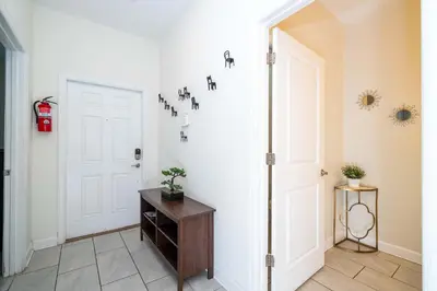 a hallway with a white door and a wooden table at Stunning 5 Bd Home w/ Pool Close to Disney 4822 in Kissimmee