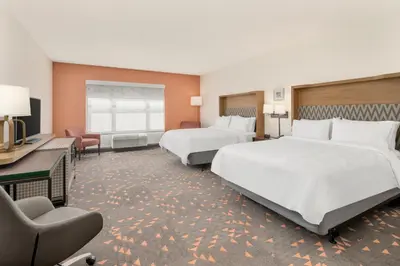 a hotel room with two beds and a desk at Holiday Inn & Suites Orlando - I-Drive - Theme Parks by IHG in Orlando