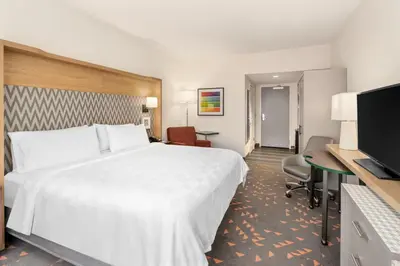 a hotel room with a large bed and a desk at Holiday Inn & Suites Orlando - I-Drive - Theme Parks by IHG in Orlando