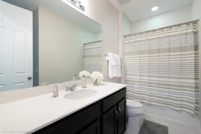 a bathroom with a sink and a toilet and a mirror at Sunshine Ridge Loop Villa #258891 Villa in Orlando