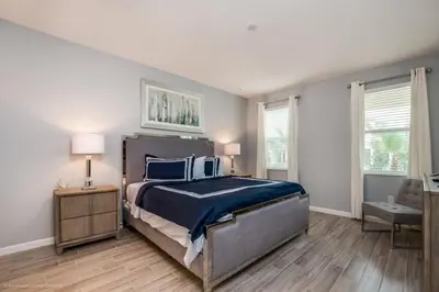 a bedroom with a bed and a desk and two windows at Calistoga Avenue Villa #259830 Villa in Kissimmee