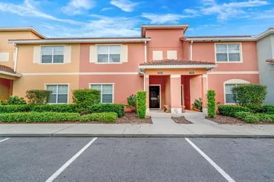 a large pink house with bushes and trees at Cuban Palm Townhouse #275805 Townhouse in Kissimmee