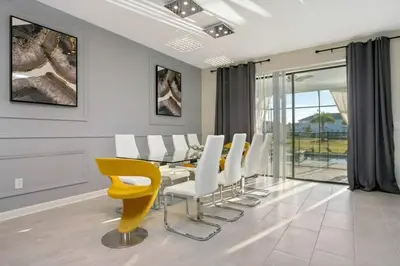 a dining room with a glass table and yellow chairs at 2901FS - Amazing 8 bedroom at Storey Lake in Kissimmee