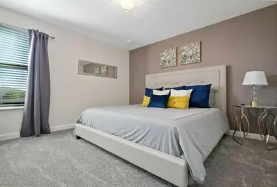 a bedroom with a bed with blue and yellow pillows at 2901FS - Amazing 8 bedroom at Storey Lake in Kissimmee