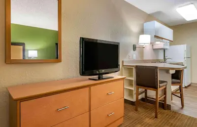 a hotel room with a television on a dresser with a desk at Extended Stay America Suites - Orlando - Altamonte Springs in Orlando