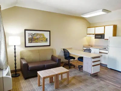 a living room with a couch and a desk and a kitchen at Extended Stay America Select Suites - Orlando - Lake Mary - 1040 Greenwood Blvd in Lake Mary