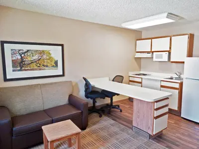 a small room with a desk and a kitchen at Extended Stay America Select Suites - Orlando - Lake Mary - 1040 Greenwood Blvd in Lake Mary